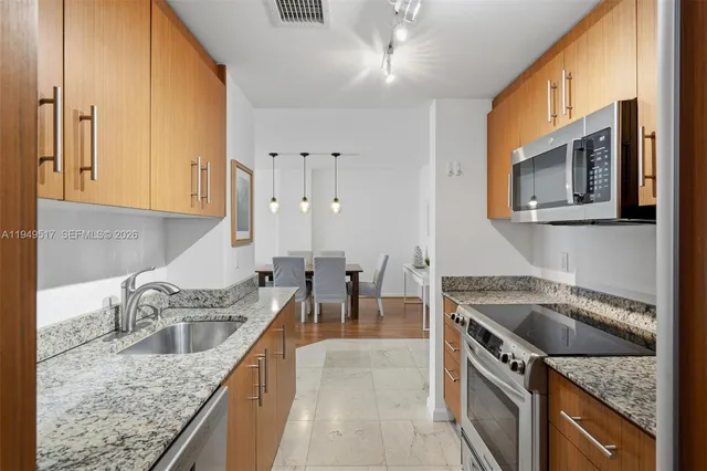 a kitchen with granite countertop a sink a stove and cabinets