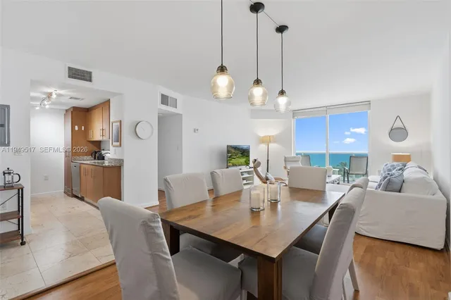 a view of a dining room and livingroom with furniture wooden floor a chandelier
