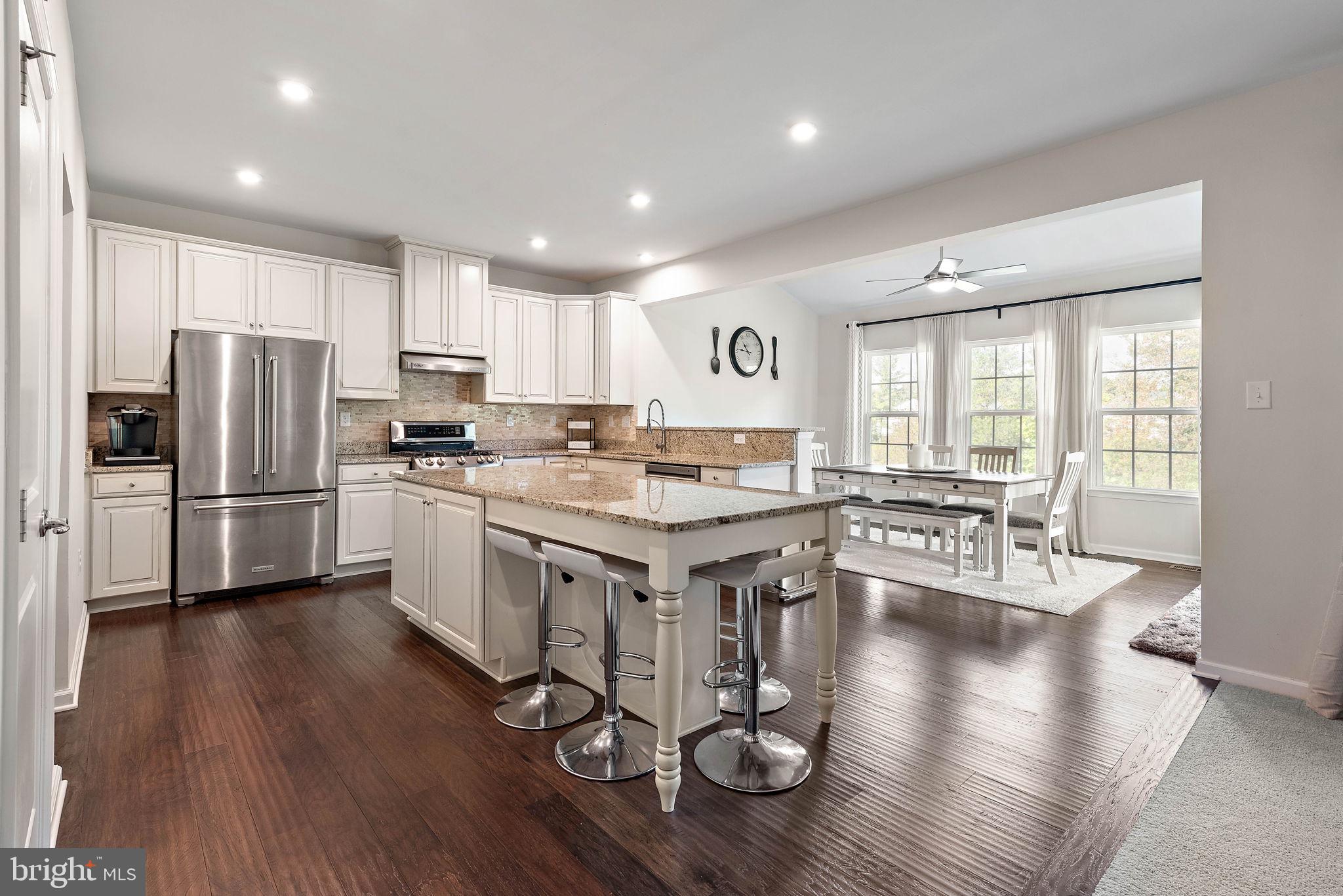 102 Pixie Moss Road Pottstown, PA 19464 - Photo 15 of 45 a kitchen with a center island wooden floor stainless steel appliances and windows