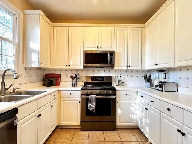 a kitchen with stainless steel appliances granite countertop white cabinets a sink and a stove