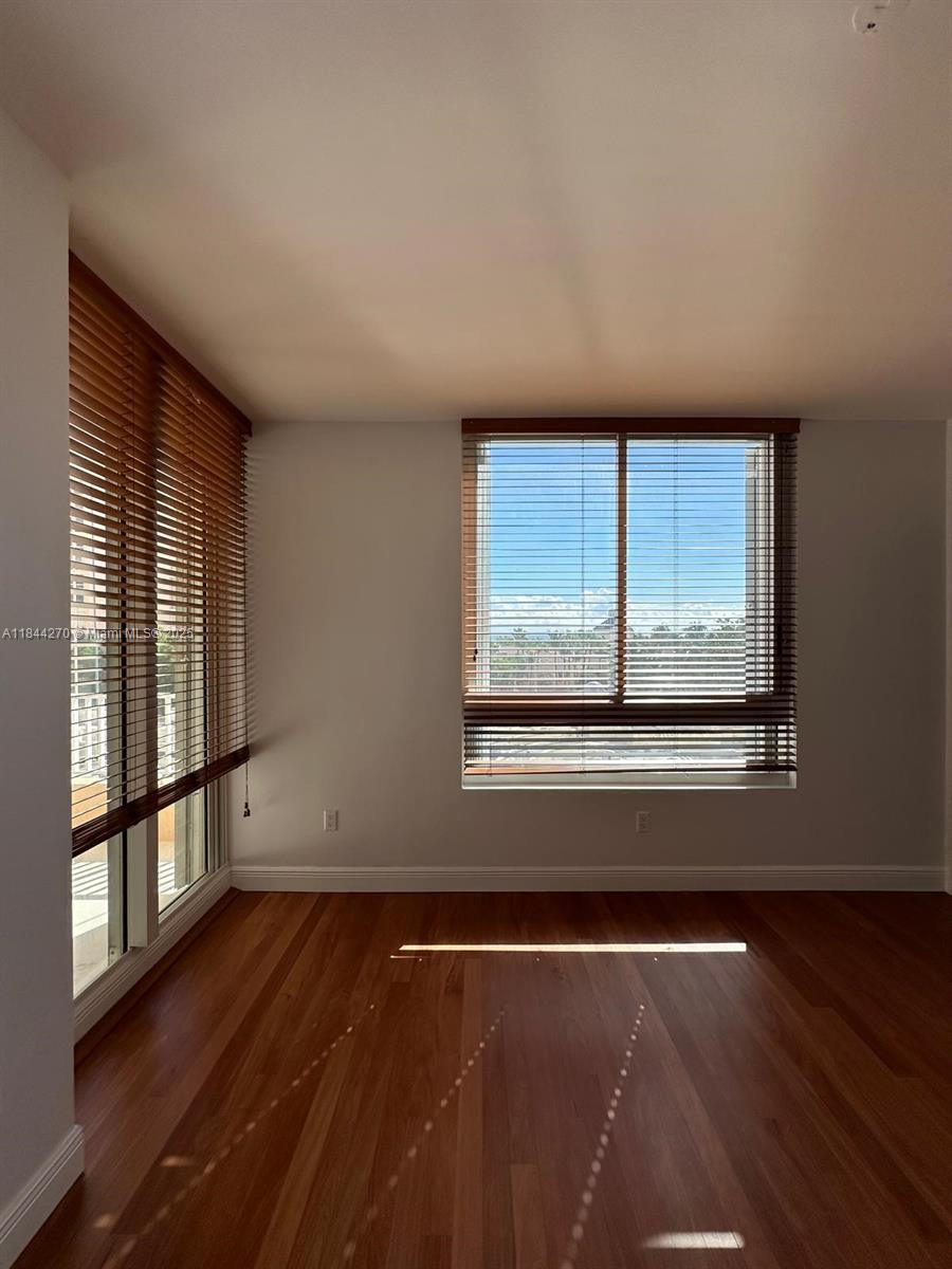 785 Crandon Boulevard, Unit 506 Key Biscayne, FL 33149 - Photo 28 of 58 an empty room with wooden floor and windows