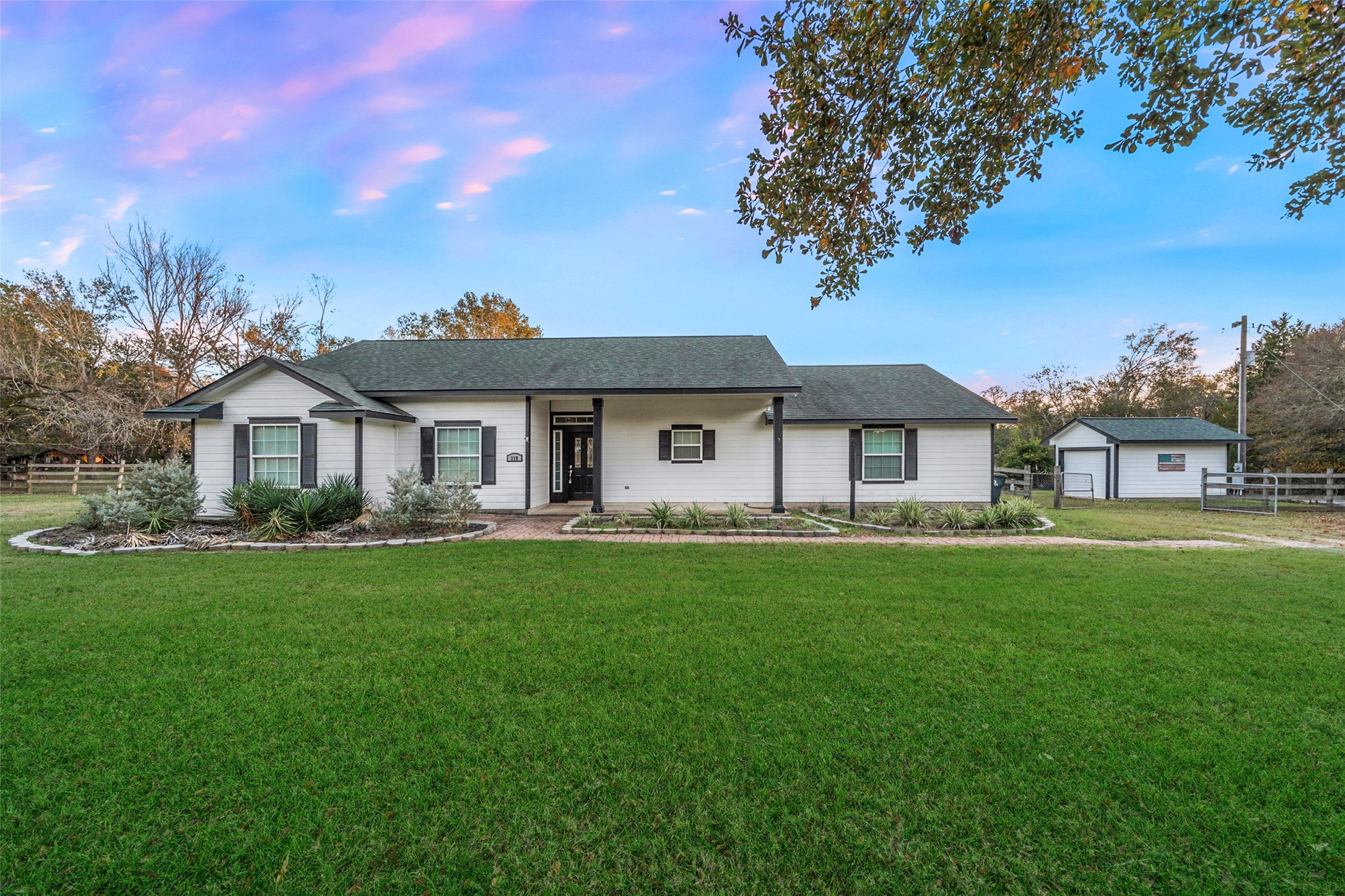 Charming single-story home with manicured lawn, covered front porch, and detached workshop.