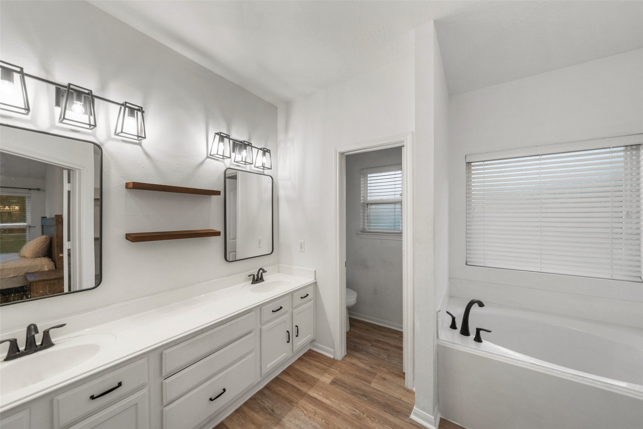 118 Pin Oak Lane Hempstead, TX 77445 - Photo 18 of 29 Updated primary bathroom featuring a dual-sink vanity, modern lighting, floating shelves, and ample storage.