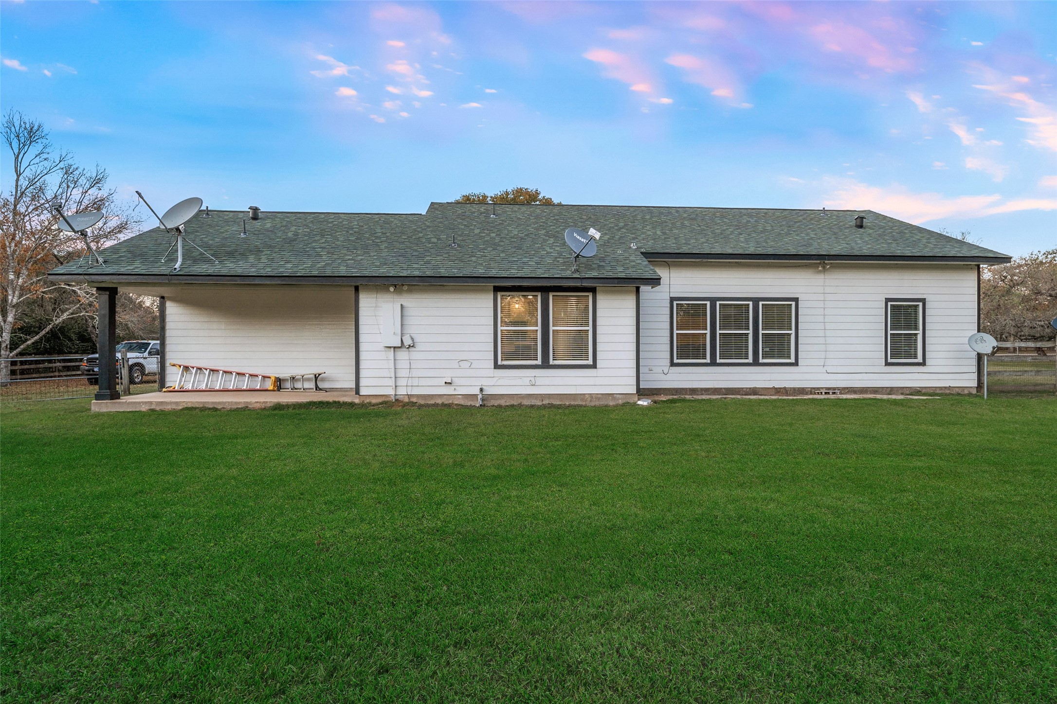 118 Pin Oak Lane Hempstead, TX 77445 - Photo 26 of 29 Rear exterior of the home with expansive lawn space and multiple windows providing natural light throughout.