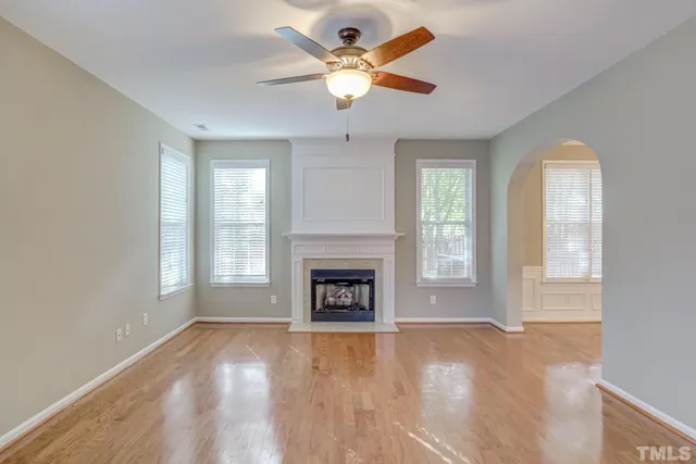 an empty room with chandelier fan and windows