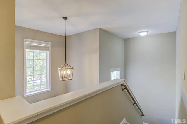 a view of a hallway with windows and chandelier