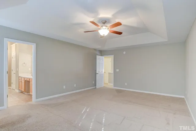 a view of an empty room with chandelier fan and a window