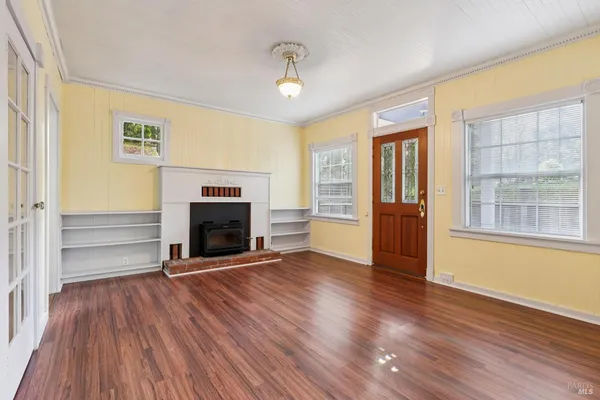 an empty room with wooden floor chandelier and windows