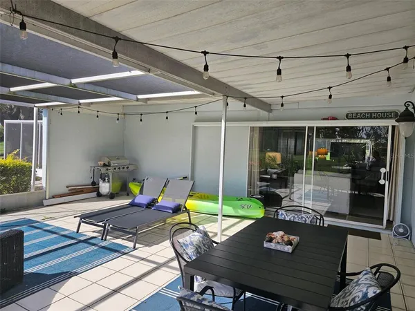 a view of a patio with table and chairs potted plants with wooden floor and floor to ceiling window