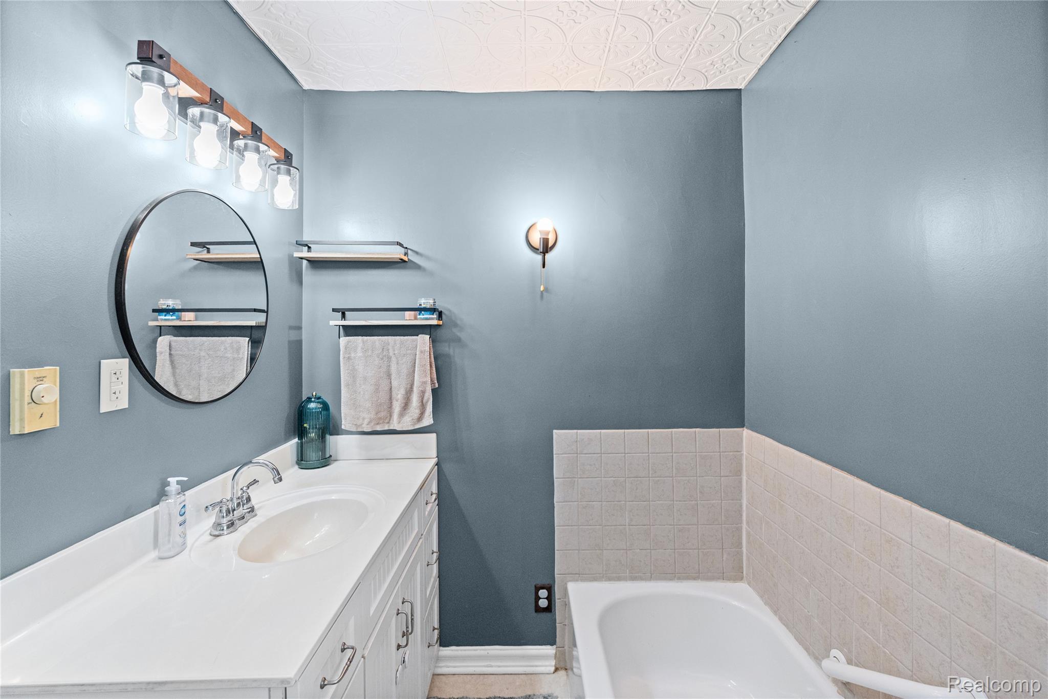 1175 South Morrish Road Flint, MI 48532 - Photo 34 of 72 Bathroom featuring a white vanity with an integrated sink, chrome faucet, and a round black-framed mirror