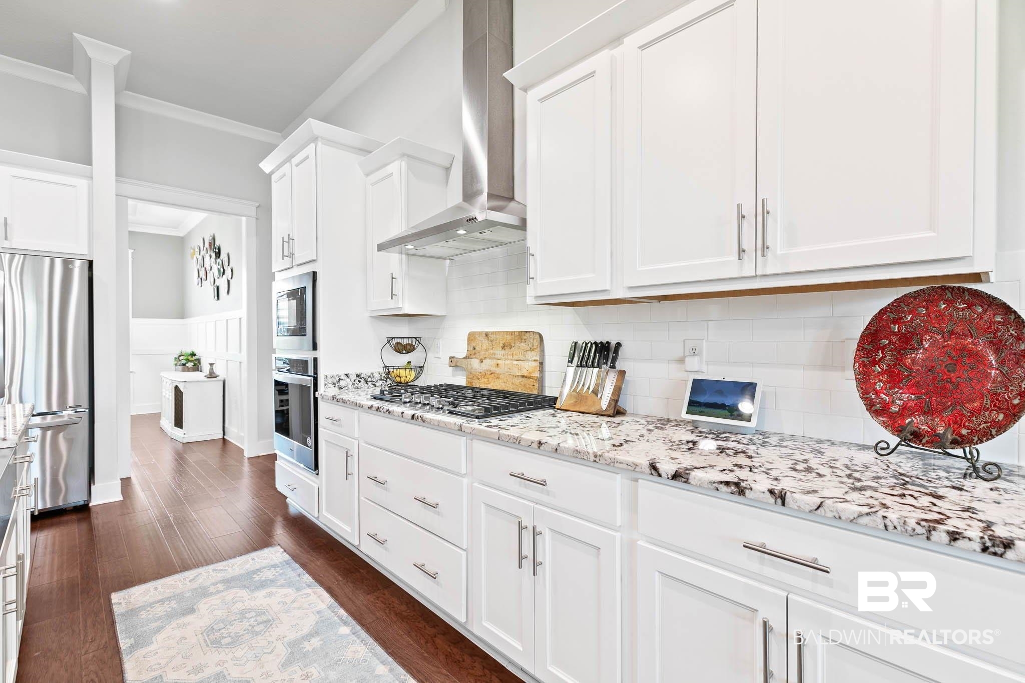 12785 Warbler Street Daphne, AL 36527 - Photo 2 of 53 Kitchen featuring stainless steel appliances, dark wood finished floors, white cabinets, wall chimney range hood, and decorative backsplash