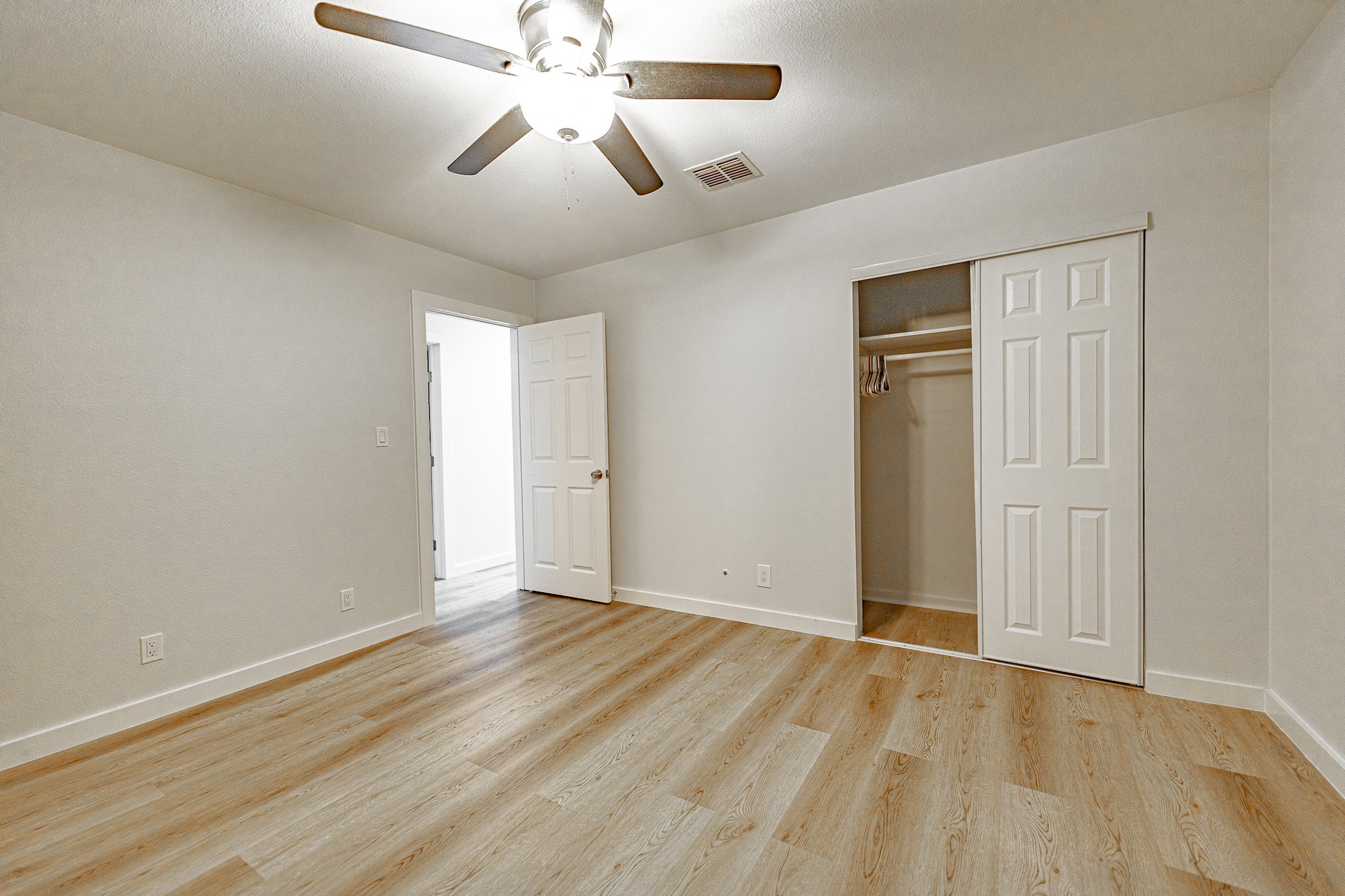 421 West Runk Street Shiner, TX 77984 - Photo 9 of 18 an empty room with wooden floor chandelier fan and closet area