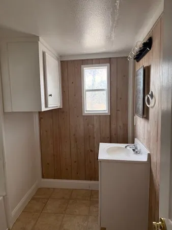 an empty room with wooden floor and windows with curtains