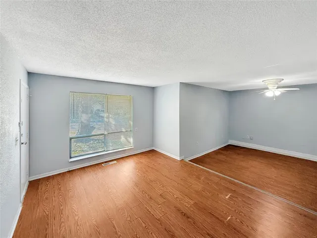 an empty room with wooden floor and chandelier fan