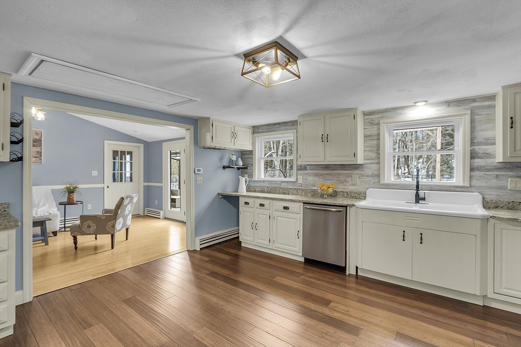 816 Patriots Road Templeton, MA 01468 - Photo 12 of 34 a kitchen with a stove a sink and white cabinets with wooden floor