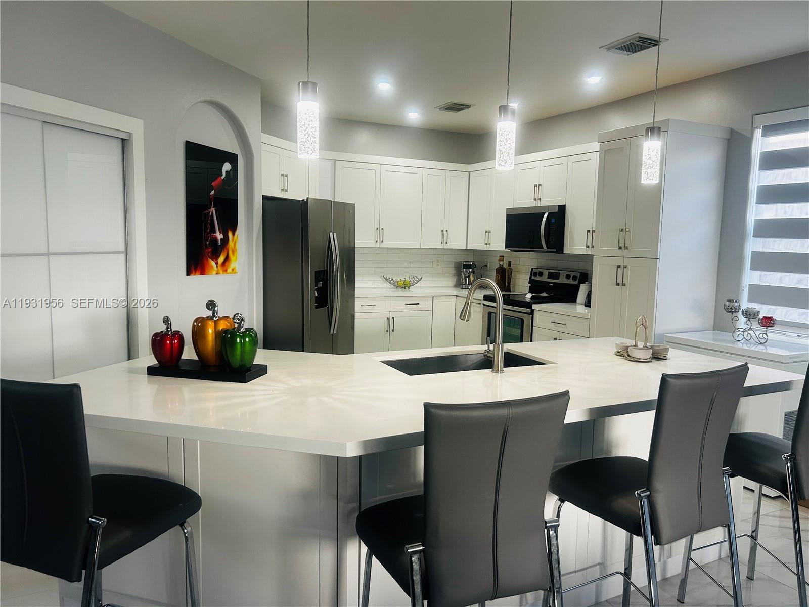 13995 Southwest 154th Street Miami, FL 33177 - Photo 2 of 27 a kitchen with stainless steel appliances a dining table chairs microwave and sink