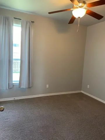 an empty room with a window and a fan