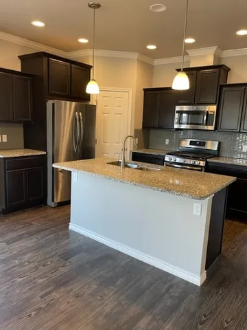 a large kitchen with kitchen island a large counter top stainless steel appliances and cabinets