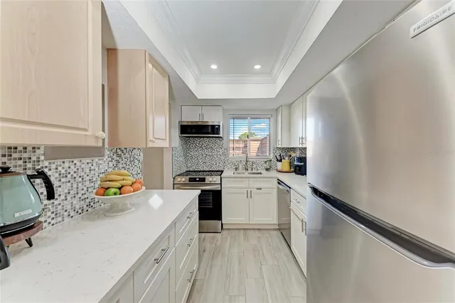 a kitchen with a sink a refrigerator and white cabinets