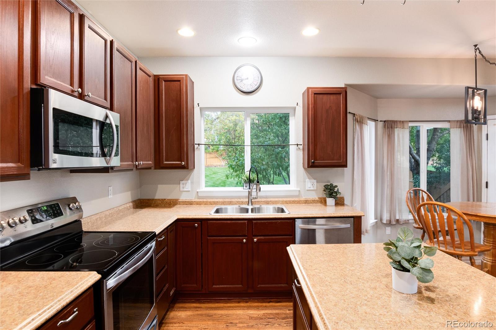 9218 Fox Fire Lane Highlands Ranch, CO 80129 - Photo 11 of 38 a kitchen with stainless steel appliances granite countertop a stove top oven a sink dishwasher a dining table and chairs with wooden floor