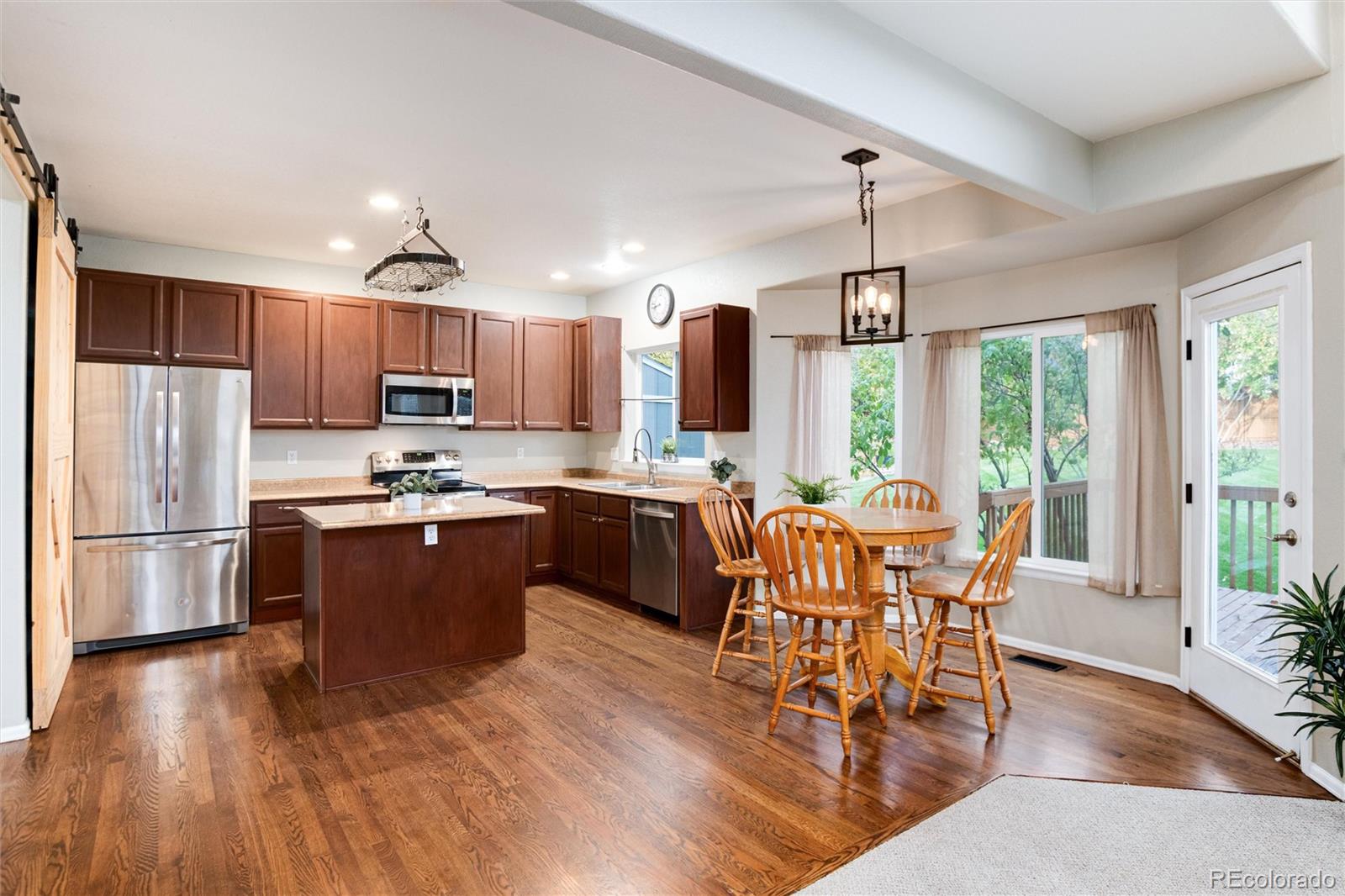 9218 Fox Fire Lane Highlands Ranch, CO 80129 - Photo 9 of 38 a kitchen with stainless steel appliances granite countertop a refrigerator a stove top oven a sink dishwasher a dining table and chairs with wooden floor