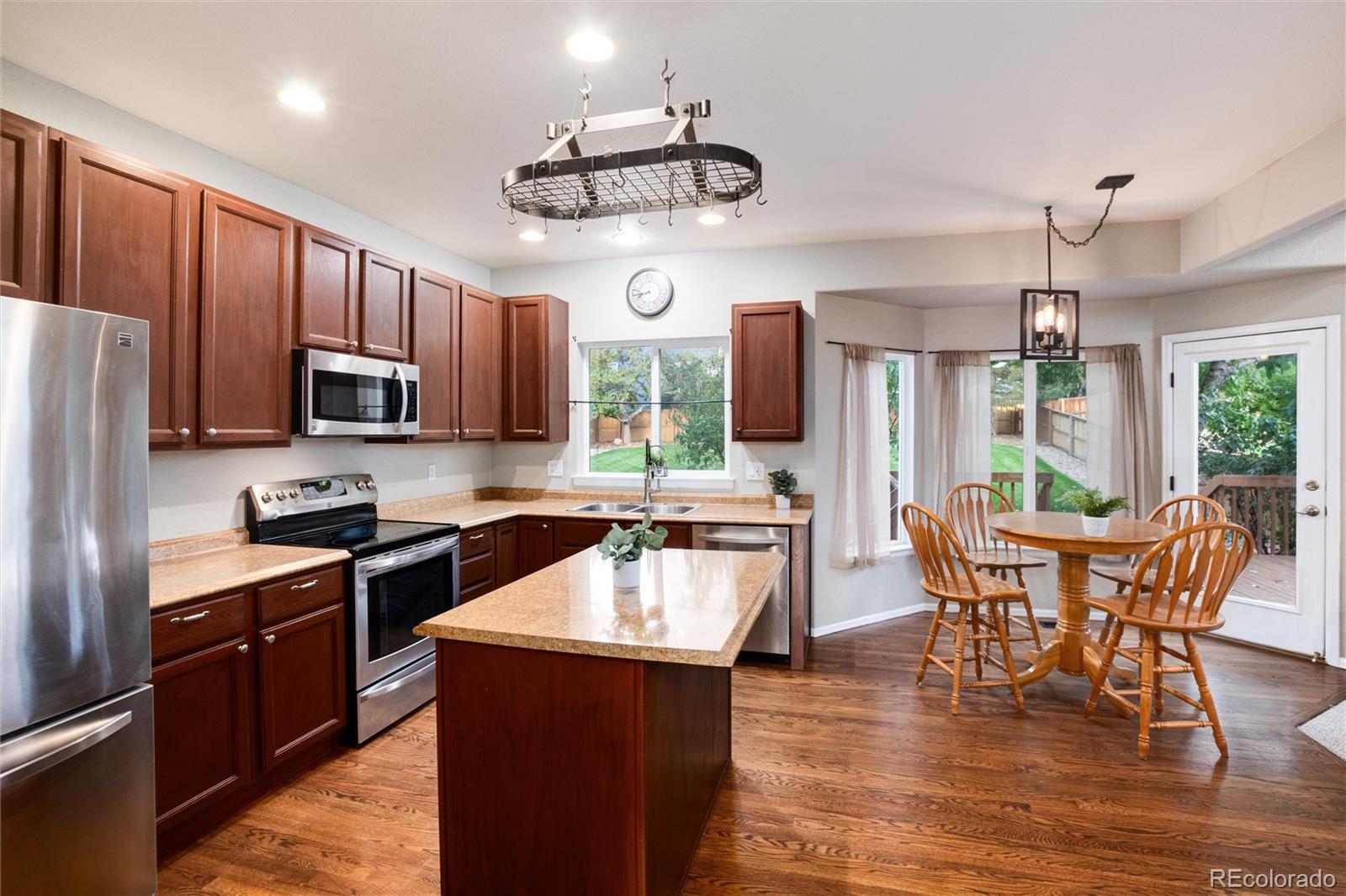 9218 Fox Fire Lane Highlands Ranch, CO 80129 - Photo 10 of 38 a kitchen with stainless steel appliances granite countertop a stove top oven a sink dishwasher a dining table and chairs with wooden floor