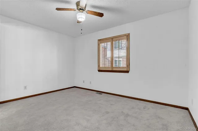 an empty room with a window and a ceiling fan
