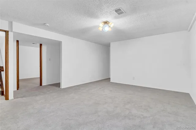 an empty room with a chandelier fan and windows