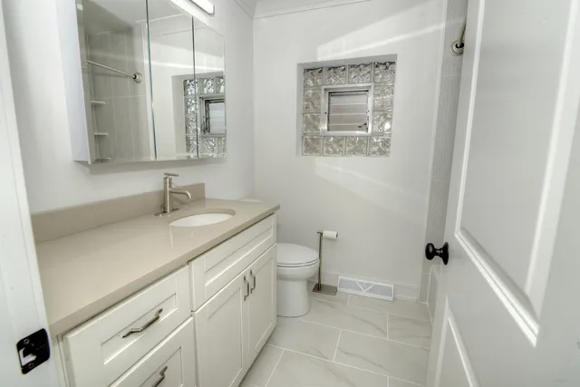 a bathroom with a granite countertop sink a mirror and a toilet