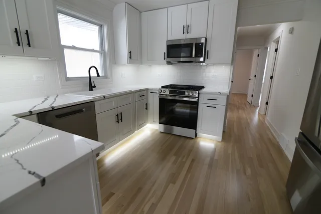 a kitchen with stainless steel appliances a sink a stove a microwave and wooden floor