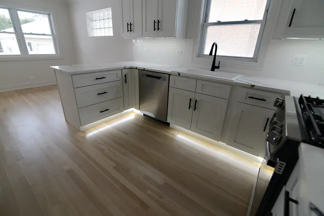 a kitchen with granite countertop a sink cabinets and wooden floor