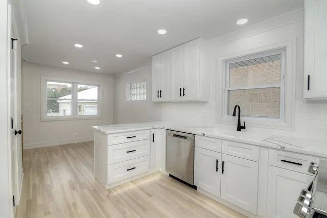 a kitchen with white cabinets and sink