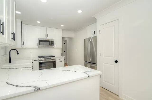 a large kitchen with stainless steel appliances a refrigerator a sink a stove a microwave and a refrigerator