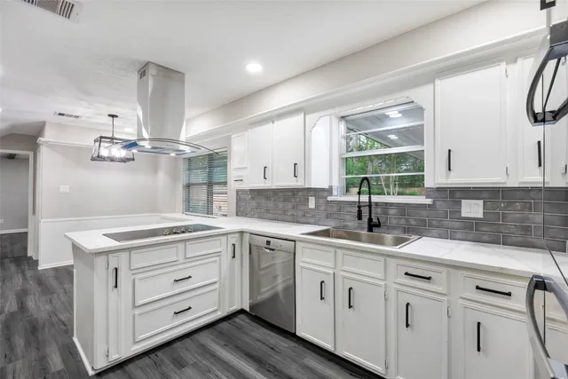 a kitchen with a sink dishwasher and white cabinets with wooden floor
