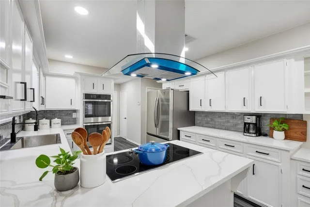 a kitchen with stainless steel appliances granite countertop a sink a stove and a refrigerator