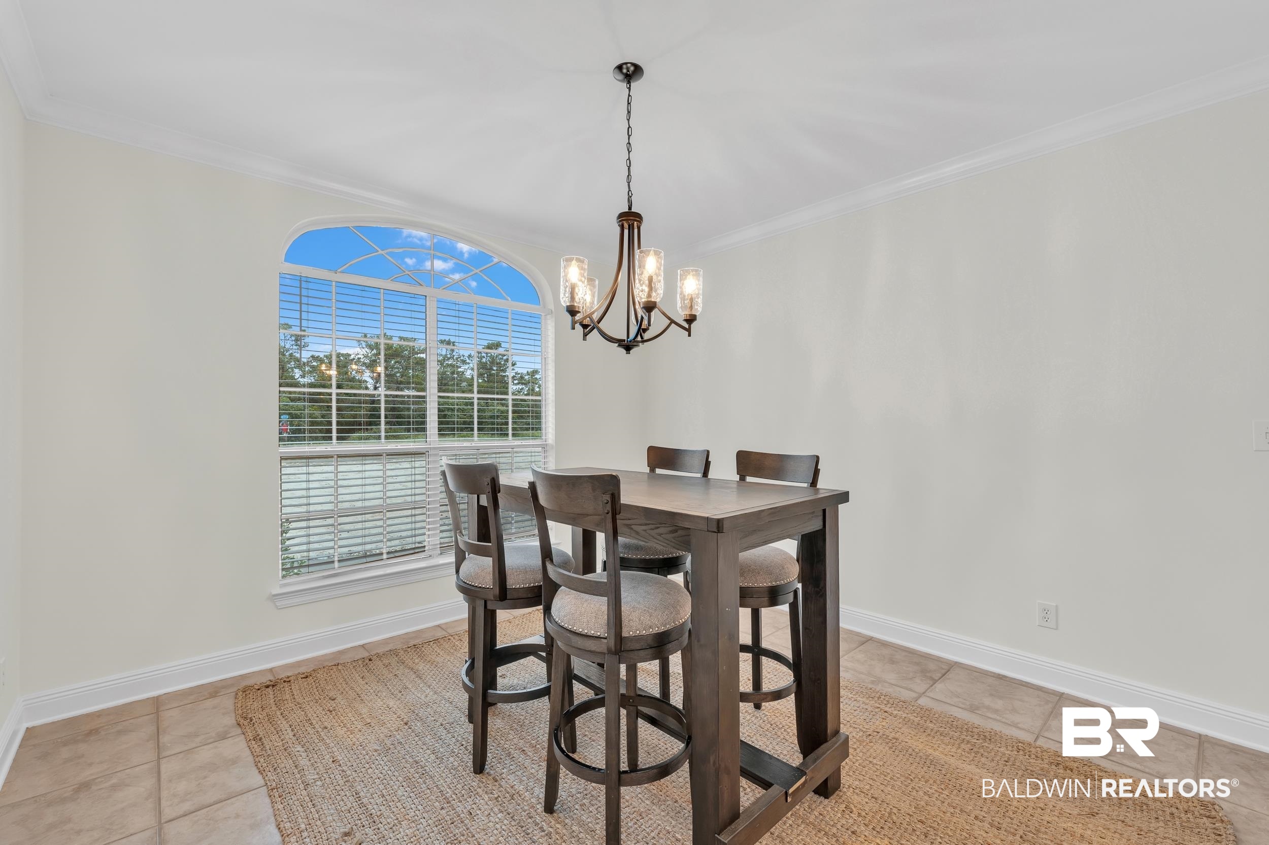 4606 Osprey Drive Orange Beach, AL 36561 - Photo 18 of 44 Dining room with a chandelier, light tile patterned floors, and crown molding