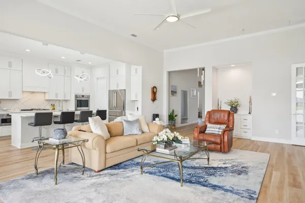 a kitchen with kitchen island a stove a sink a refrigerator and a dining table with wooden floor