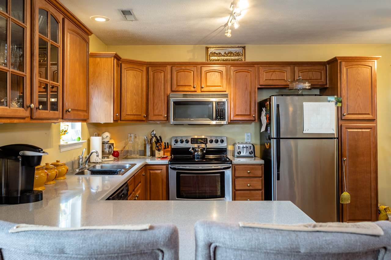 128 Gentry Road Weyers Cave, VA 24486 - Photo 9 of 48 a kitchen with stainless steel appliances granite countertop a refrigerator a stove and a sink with wooden floor