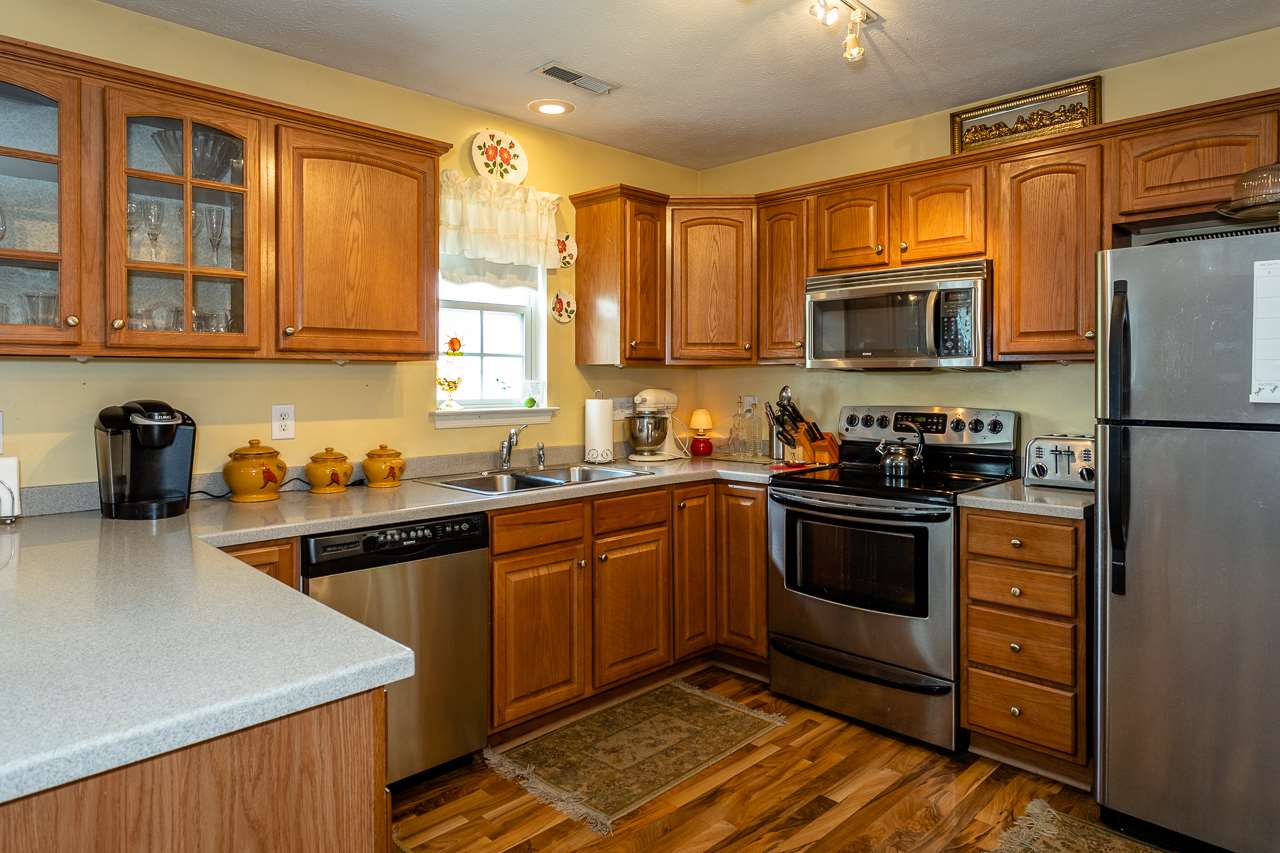 128 Gentry Road Weyers Cave, VA 24486 - Photo 10 of 48 a kitchen with stainless steel appliances granite countertop a stove top oven a sink dishwasher a refrigerator and cabinets with wooden floor