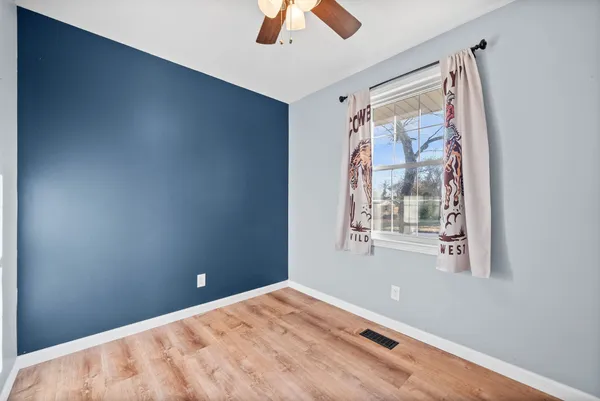 a view of an empty room with window and wooden floor