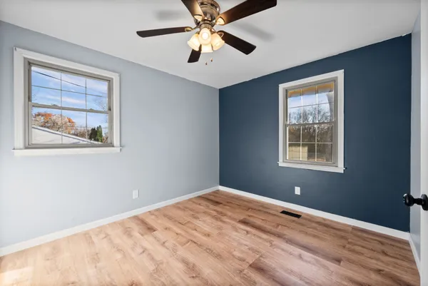 a view of an empty room with window and chandelier fan