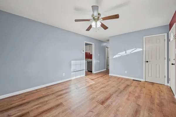 a view of empty room with wooden floor and ceiling fan