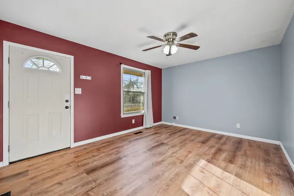 a view of an empty room with window and wooden floor