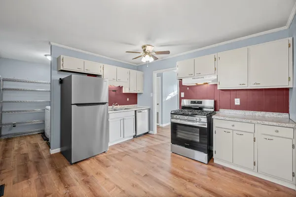 a kitchen with cabinets stainless steel appliances and wooden floor