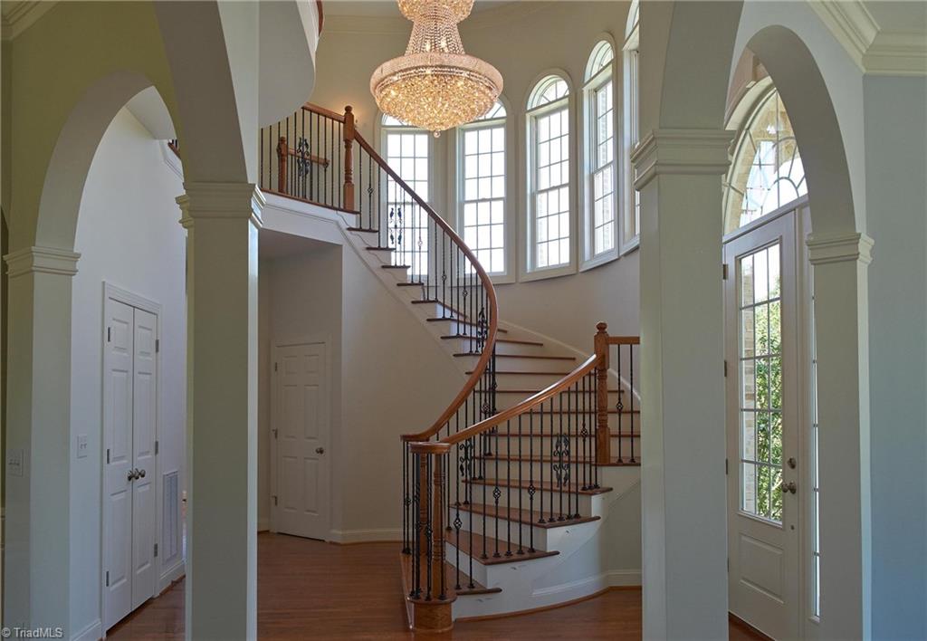 602 Bobcat Road Summerfield, NC 27358 - Photo 3 of 30 Grand entry with arched doorways and beautiful wrought iron spindles. Wet bar is behind the doors on the left, and door under stairs leads to full roughed-in unfinished basement.