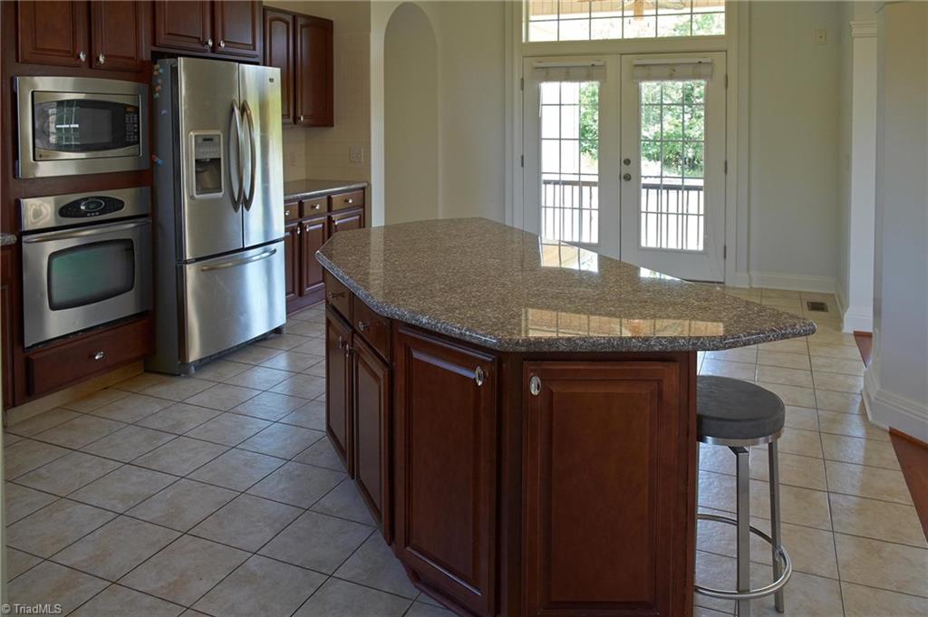 602 Bobcat Road Summerfield, NC 27358 - Photo 9 of 30 Open and spacious kitchen with french doors to a private deck. Arched doorway on the left leads into a 4 car attached garage.