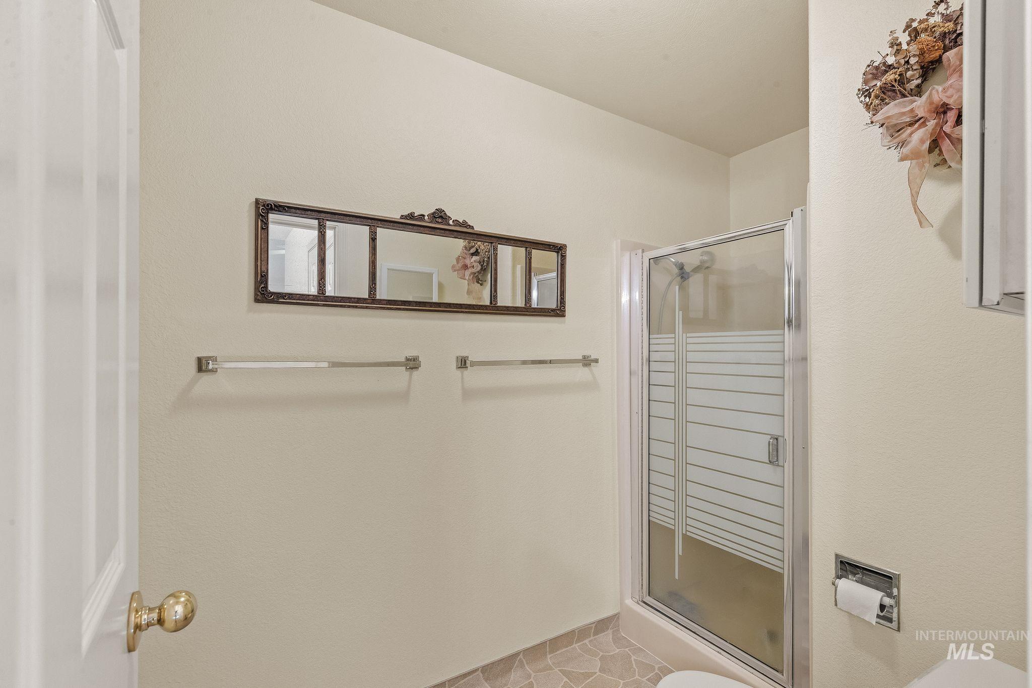 1091 Cedar Ridge Road Kendrick, ID 83537 - Photo 42 of 48 Enclosed shower with frosted glass and chrome frame, complemented by light-toned wall paint, two towel bars, and a decorative framed mirror