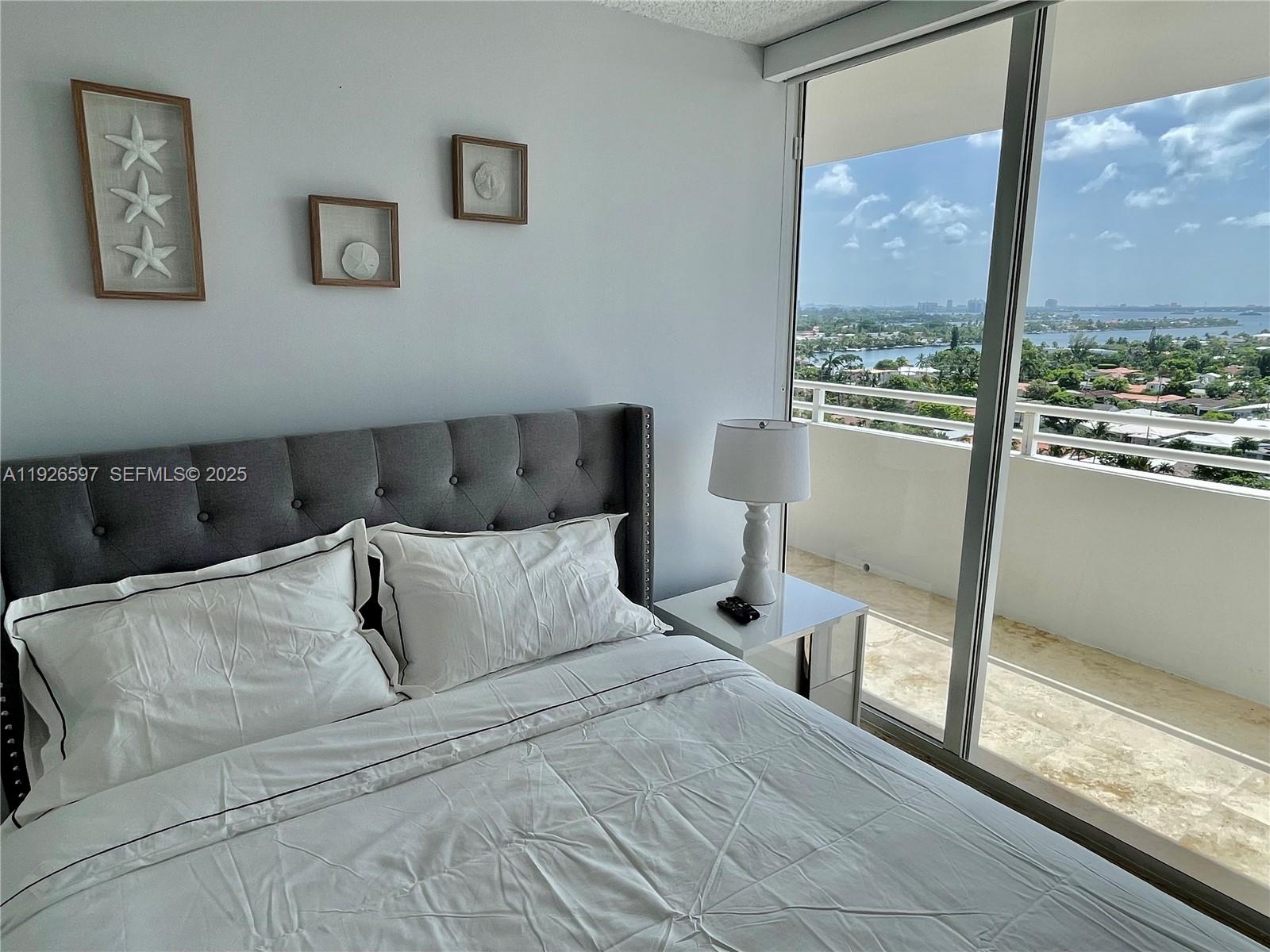 8911 Collins Avenue, Unit 1201 Surfside, FL 33154 - Photo 13 of 27 a bedroom with a bed and a large window