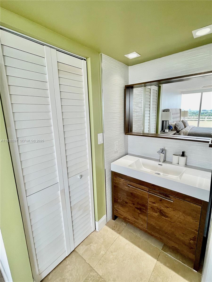 8911 Collins Avenue, Unit 1201 Surfside, FL 33154 - Photo 23 of 27 a bathroom with a granite countertop sink a mirror and a shower