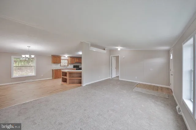 a view of an empty room with kitchen and window